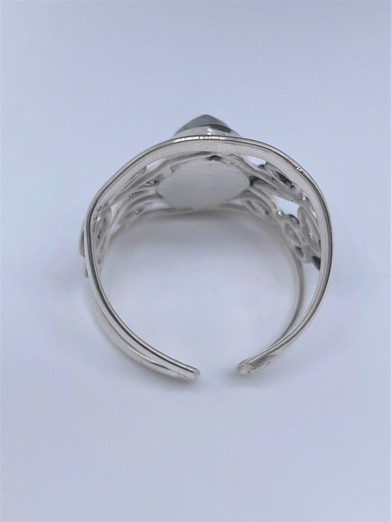 The mysterious glow of this oval moonstone cabochon is beautifully presented in this textured and polished sterling silver ring. It will make a gorgeous statement with any ensemble. 1" wide. Moonstone scrollwork ring.