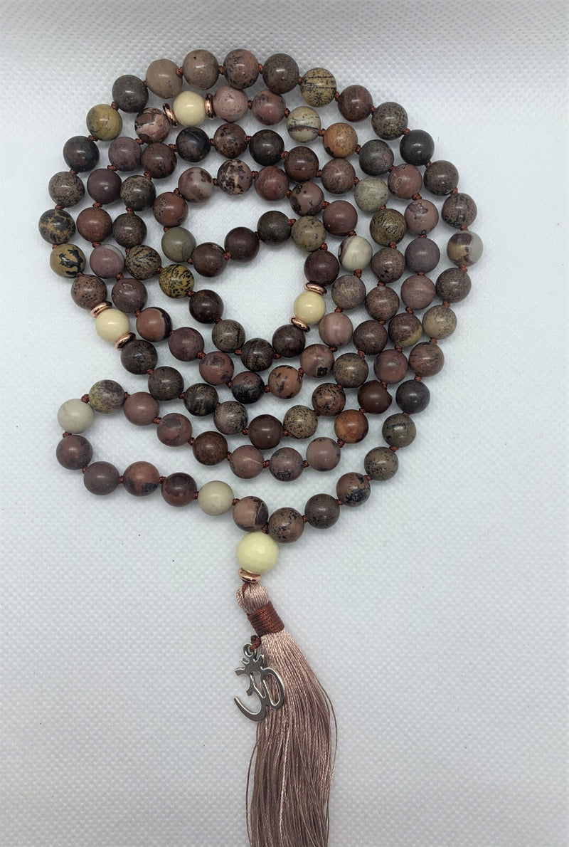 "Mynd-Kindness" is an exclusive 108 hand-made mala necklace that features Picasso Jasper stones with the Om symbol as a pendant.